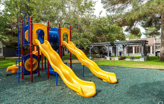 A playground with a yellow slide and a blue and red structure.