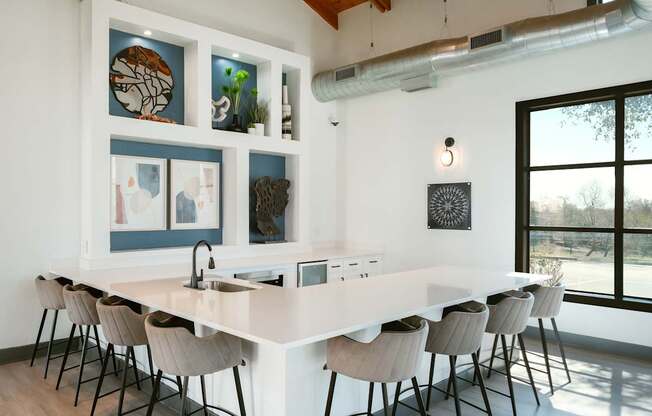 A kitchen with a long white island and chairs.