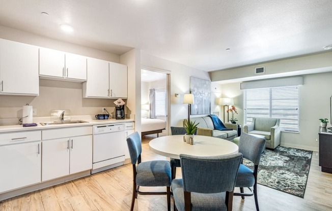 a kitchen with white cabinets and a table and chairs at Parks Residential - Denver, Centennial, CO 80111