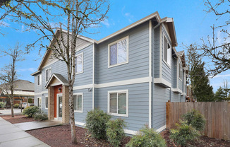 A grey house with a red door and windows.