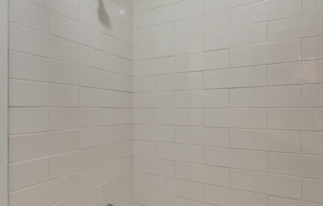 a bathroom with a white tub and a white tiled wall