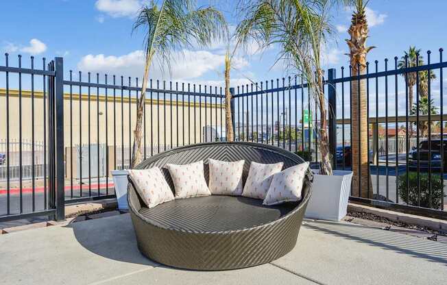 A black metal fence surrounds a circular wicker sofa.