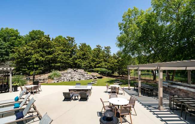 a patio with tables and chairs and a grassy area with trees