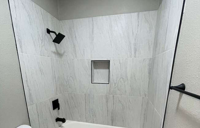 A white toilet in a bathroom with a marble tile wall.