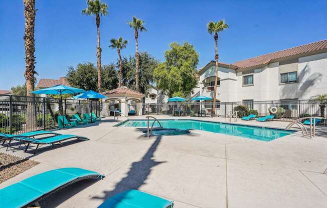 A pool surrounded by palm trees and sun loungers.