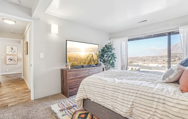 A bedroom with a large bed and a view of the mountains outside the window.