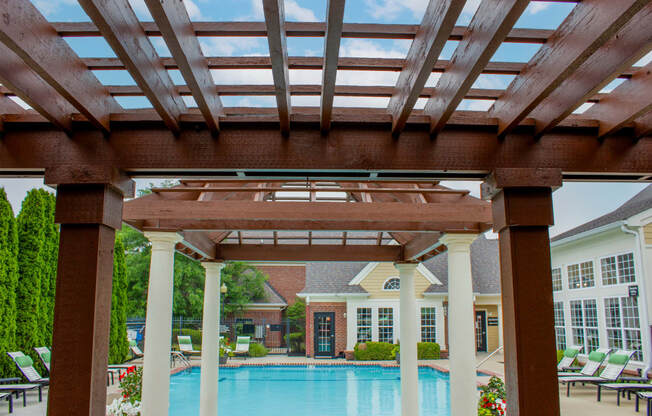 a pergola with a pool in the background