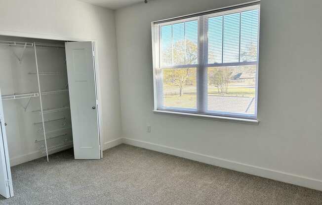 a bedroom with a large window and a closet  at Signature Pointe Apartment Homes, Athens, AL