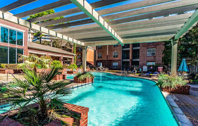 A pool under a white canopy with a building in the background.