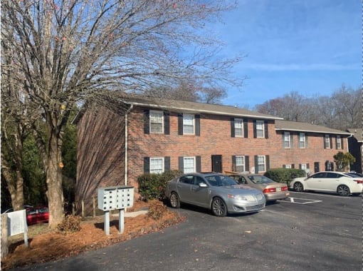 a brick apartment building with cars parked in a parking lot