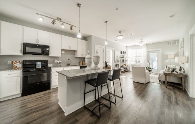 an open kitchen and living room with a marble counter top