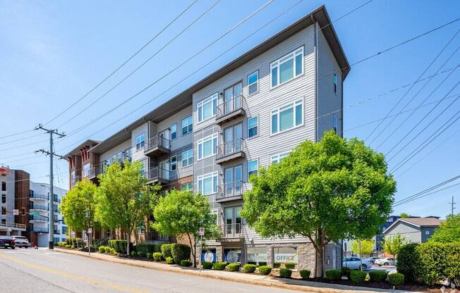 an apartment building on the corner of a street with trees