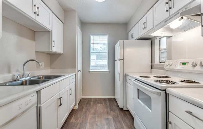 an empty kitchen with white appliances and white cabinets