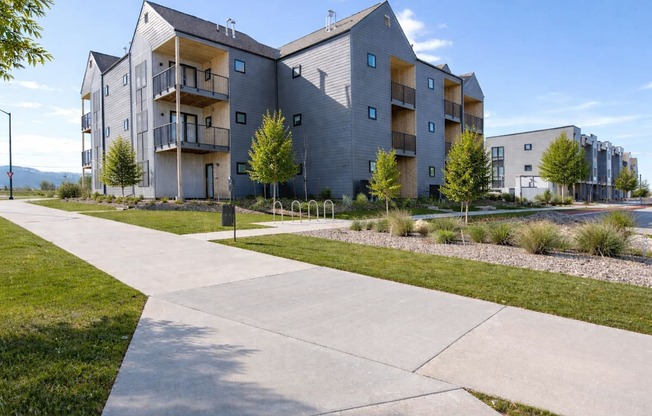 A modern apartment complex with a concrete walkway in front.