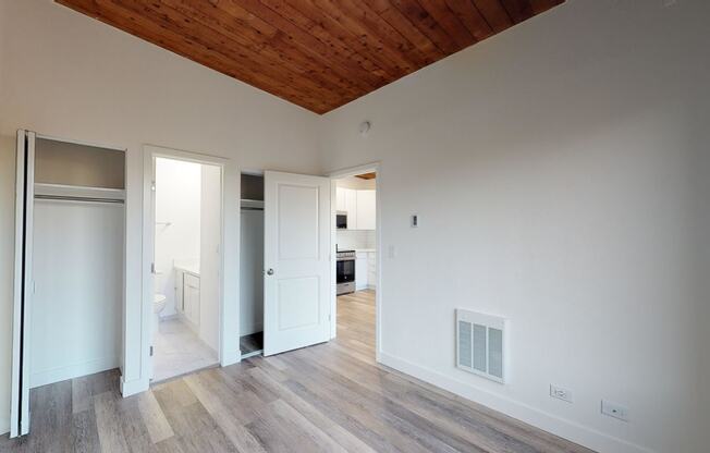 a bedroom with white walls and a wooden ceiling