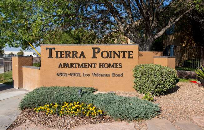 a sign for terra pointe apartment homes in front of a sidewalk and plants