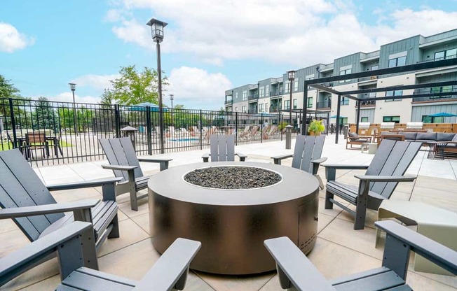 A conversational fire pit with several Adirondack chairs surrounding it.