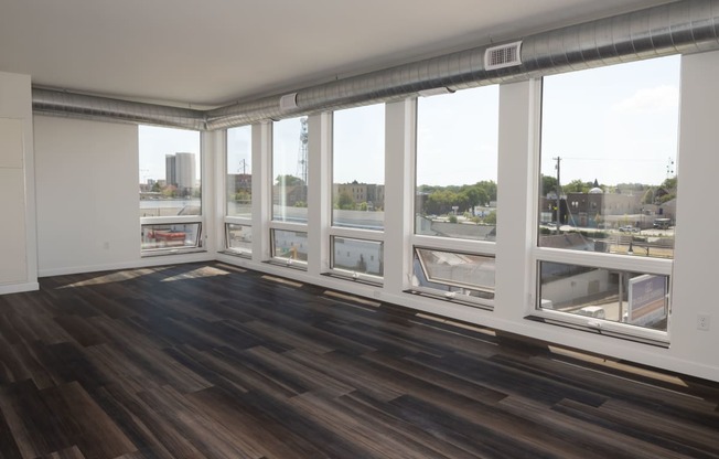 A living room with hardwood floors and a large window with a view of a city at The Landing at 1001 NP, Fargo, ND, 58102