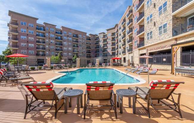 a swimming pool with patio furniture in front of an apartment building