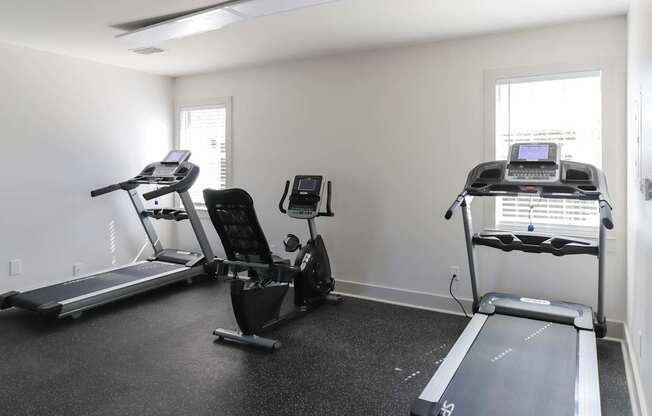 A room with a treadmill, a stationary bike, and a rowing machine.