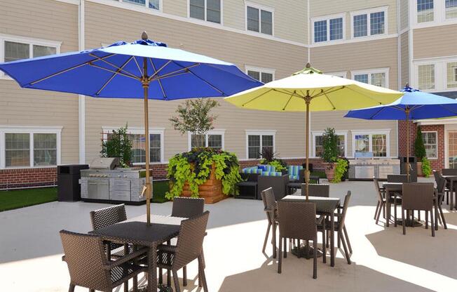 a patio with tables and umbrellas in front of a building