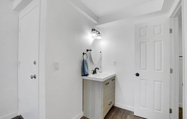 A white bathroom with a sink and a mirror.