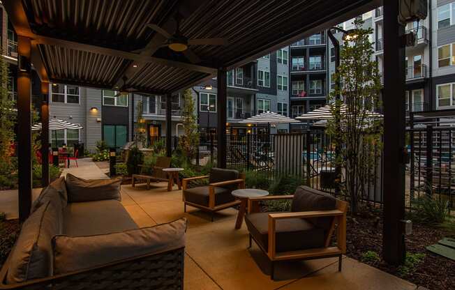 a patio with a couch and chairs and tables in front of an apartment building