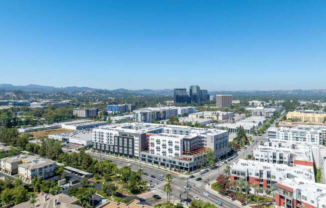A cityscape with a mix of residential and commercial buildings under a clear blue sky.