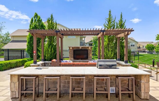 a large outdoor kitchen with a bar and a fireplace