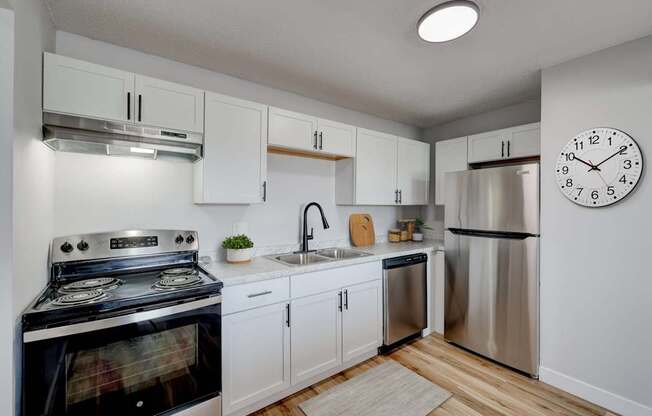 A modern kitchen with a stove, sink, and refrigerator at The Hampton Meadows Apartments, Des Moines, IA