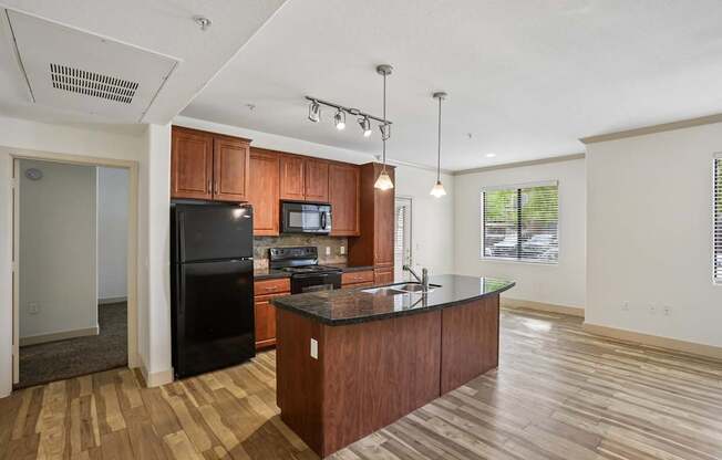 A kitchen with wooden floors and a black refrigerator.