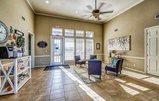 a living room with chairs and a ceiling fan