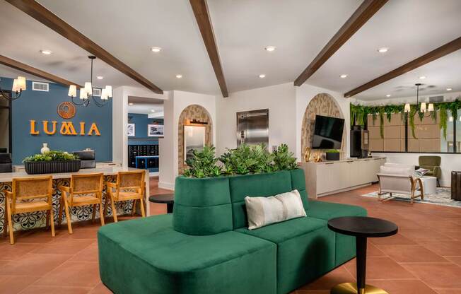 A green couch sits in the middle of a room with wooden floors and a white ceiling.