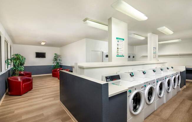 A laundromat with a row of washing machines and a red chair.