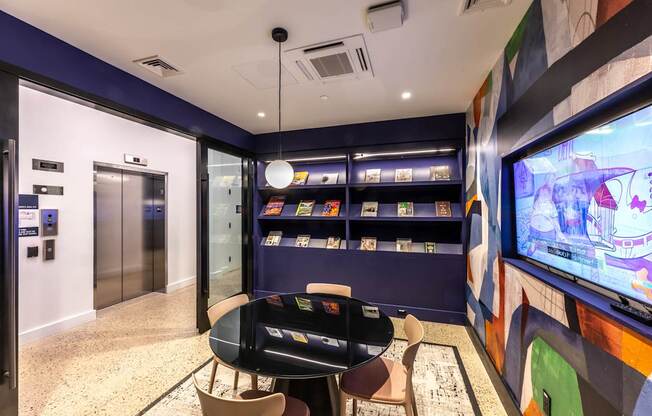 A room with a television, chairs, and a table.