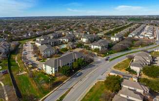 A suburban area with apartment buildings and a road with cars.