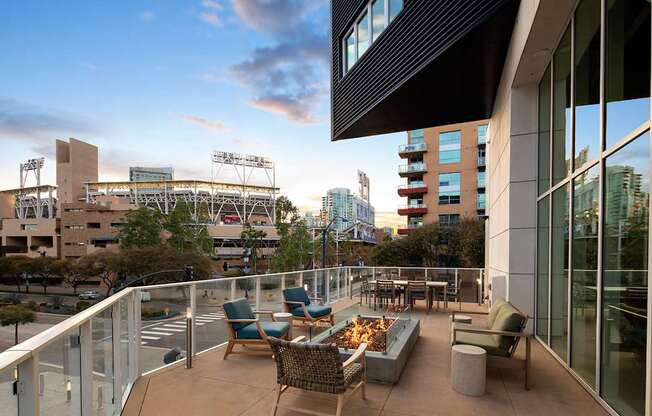 A balcony with chairs and a table overlooks a cityscape.