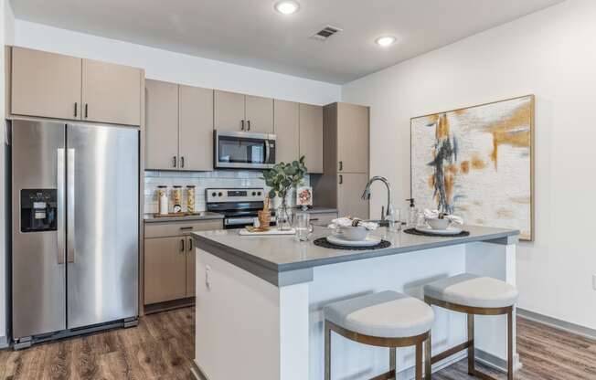 a kitchen with a large center island with two stools at Prism at Diamond Ridge, Moon Township, PA