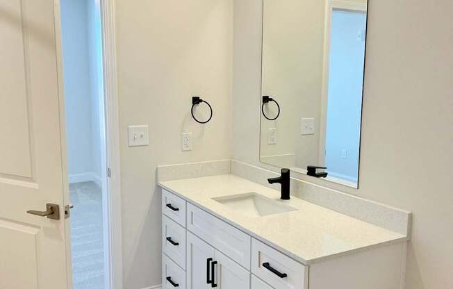 A white bathroom with a sink and mirror.