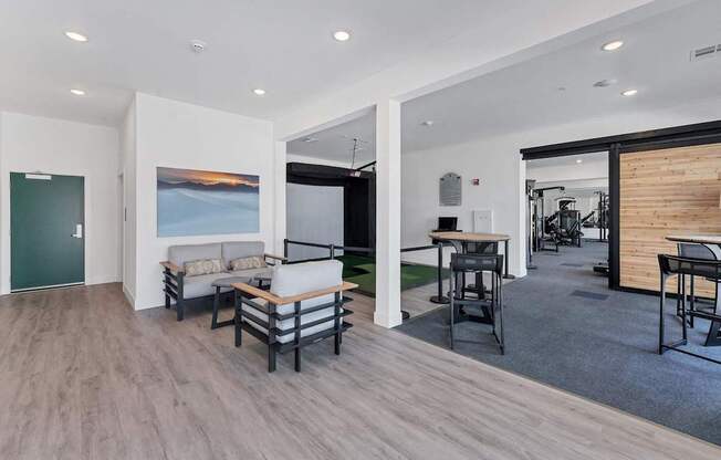 A modern living room with a couch, chairs, and a painting on the wall.