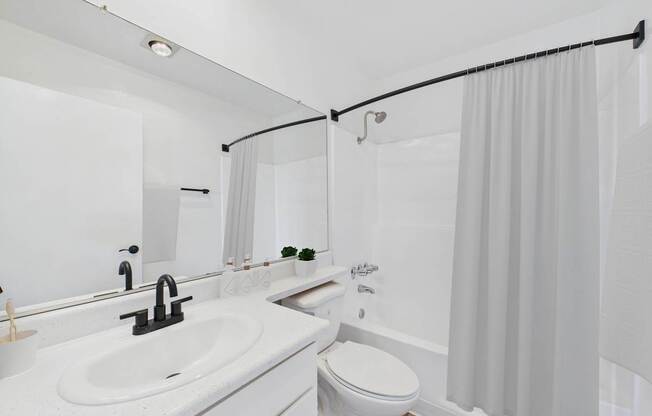 A white bathroom with a sink, toilet, and shower.