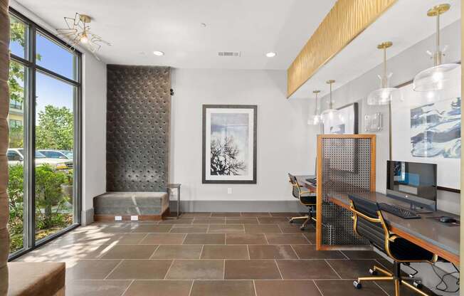 A room with a desk and chairs with a painting hanging on the wall.