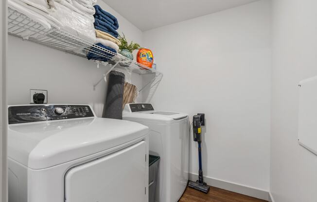 a washer and dryer in a small laundry room with white walls and wood