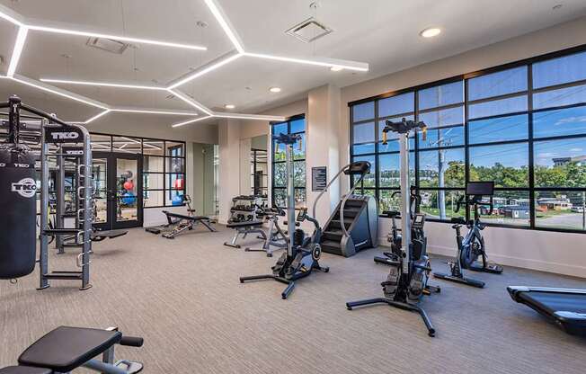 a gym with weights and cardio equipment and large windows