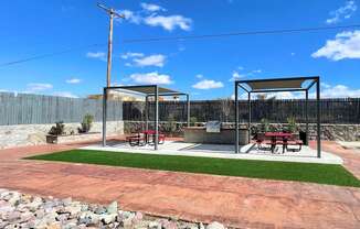 A picnic area with a table and chairs is set up in a park.