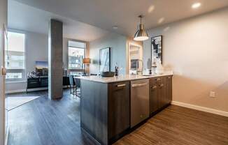 A modern kitchen with stainless steel appliances and wooden flooring.
