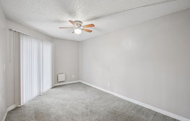 A room with a ceiling fan and carpeted floor.