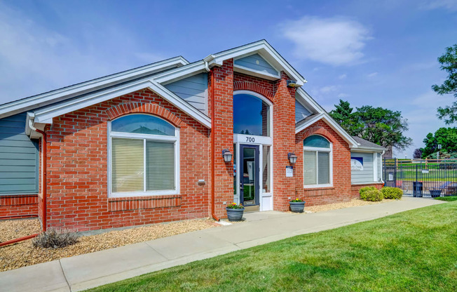 the front of a brick house with a sidewalk and grass