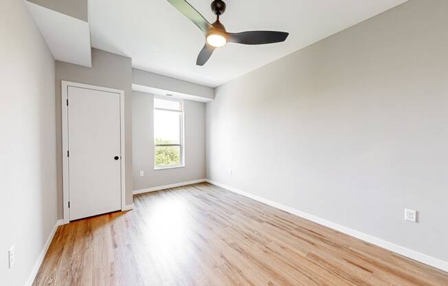 an empty living room with wood floors and a ceiling fan