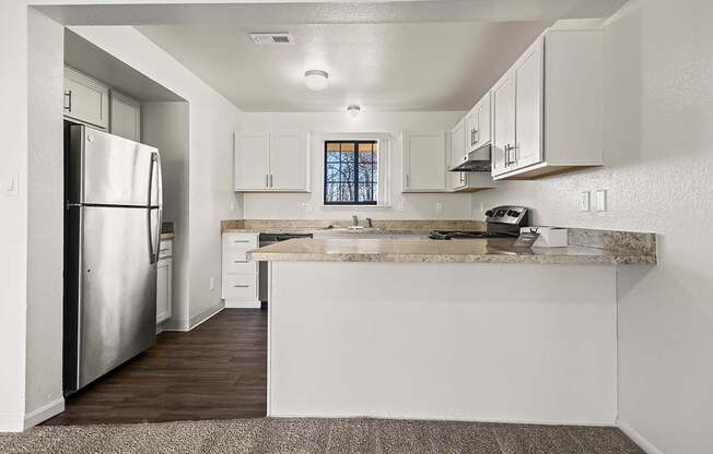 A kitchen with a stainless steel refrigerator, window, and white cabinets at Tanglewood Apartments, Oak Creek, WI